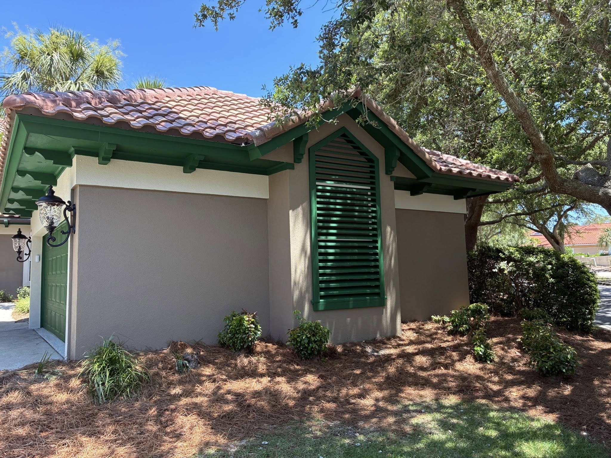 After — exterior stucco and paint completed with green trim by Harvey's Restoration