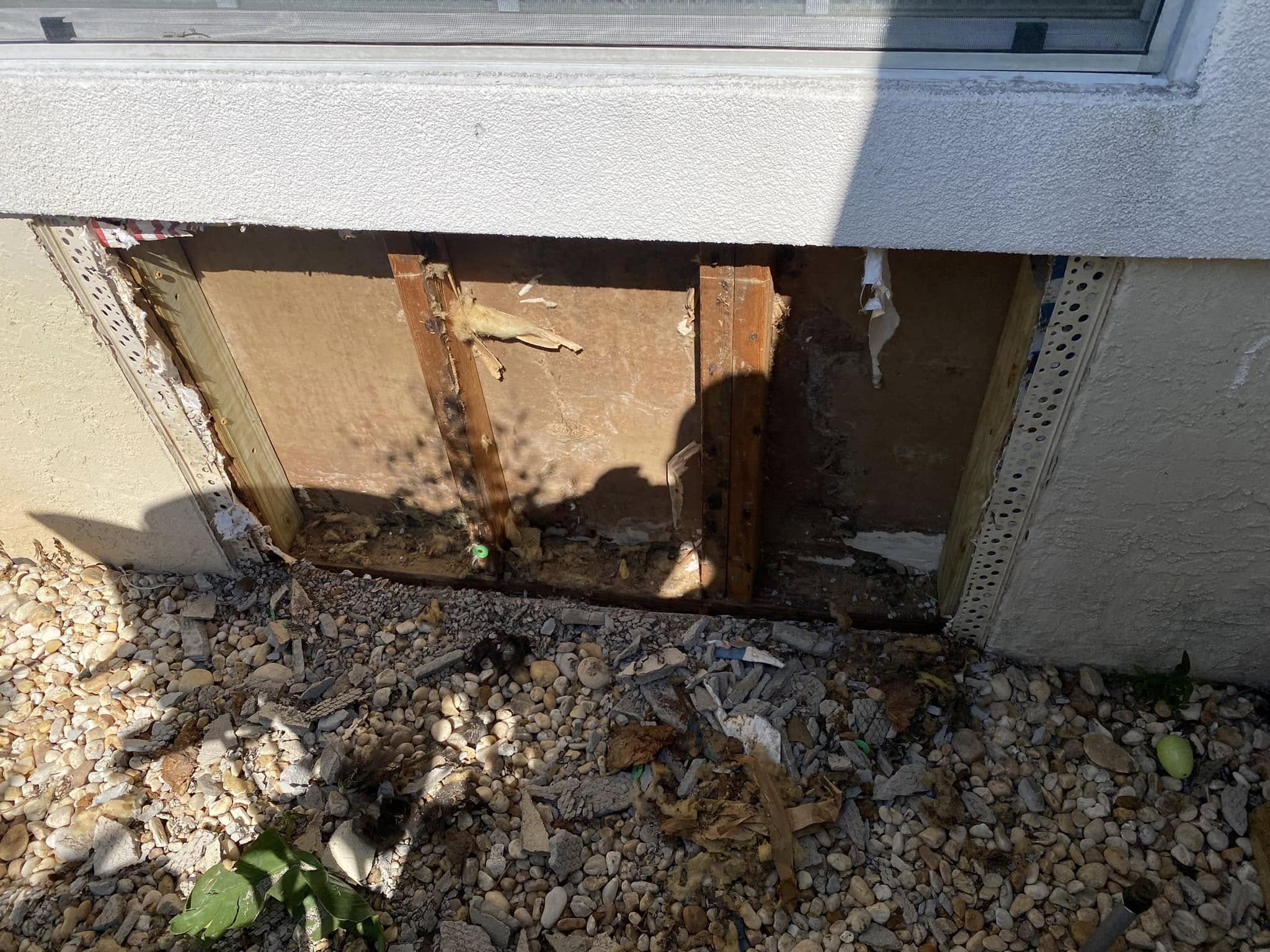 Before — stucco damage exposed, rotten framing and moisture intrusion